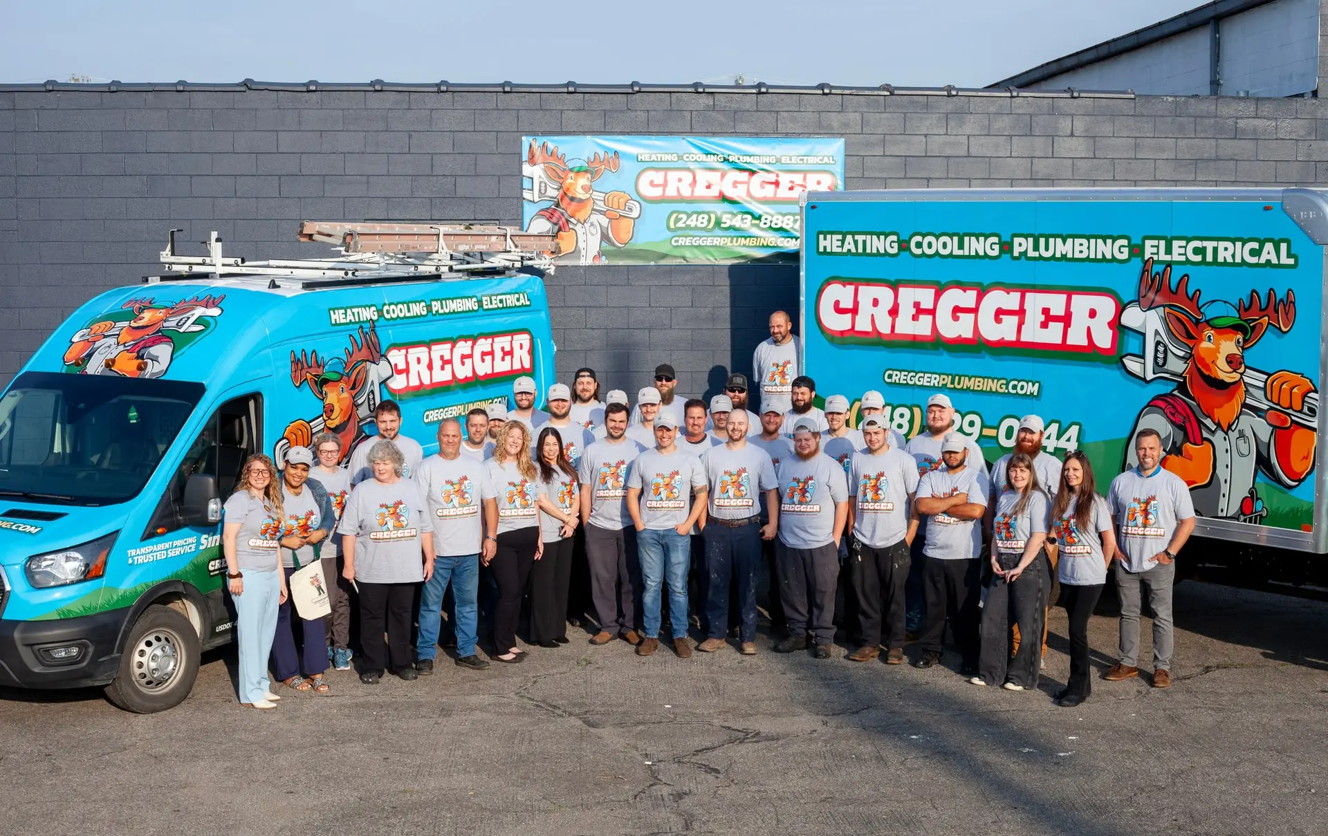 The Cregger team in matching shirts pose in front of a blue van and truck with bright Cregger branding. The mood is cheerful and cohesive.