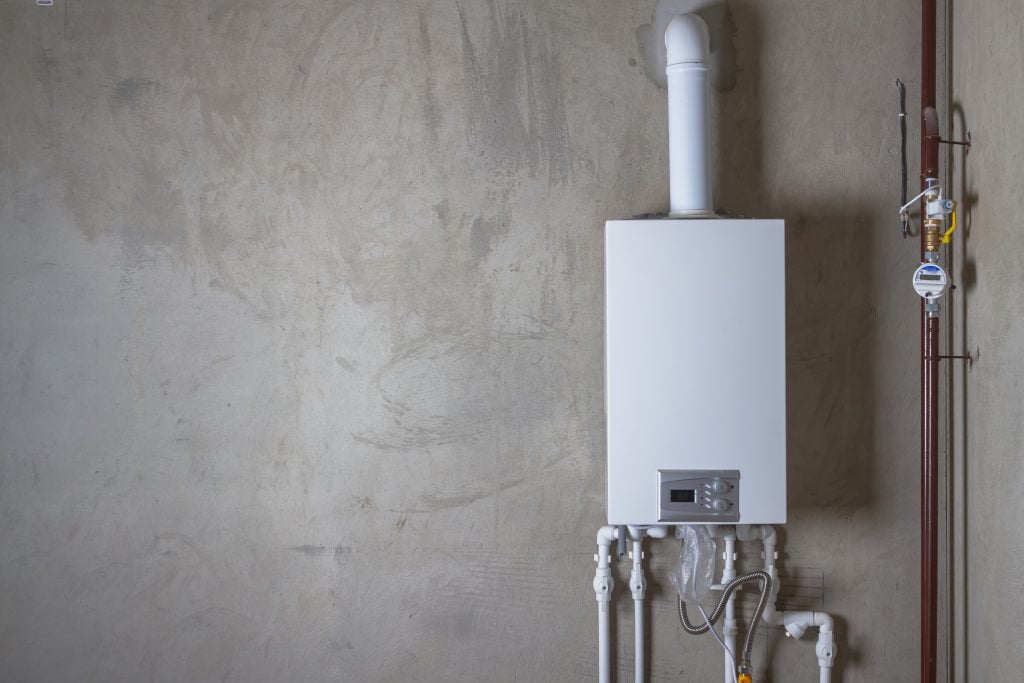 A licensed Cregger plumber installing a modern, energy-efficient tankless water heater in a Taylor basement.