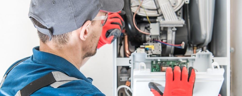 An experienced Cregger HVAC professional performing detailed furnace repair and safety testing on a multi-zone residential heating unit in Bloomfield.