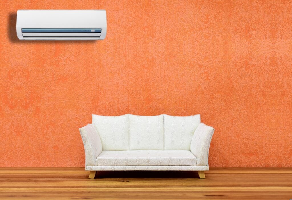 Wall-mounted air conditioning unit above a living room sofa, illustrating indoor comfort, air circulation, and air quality management in a Metro Detroit home.
