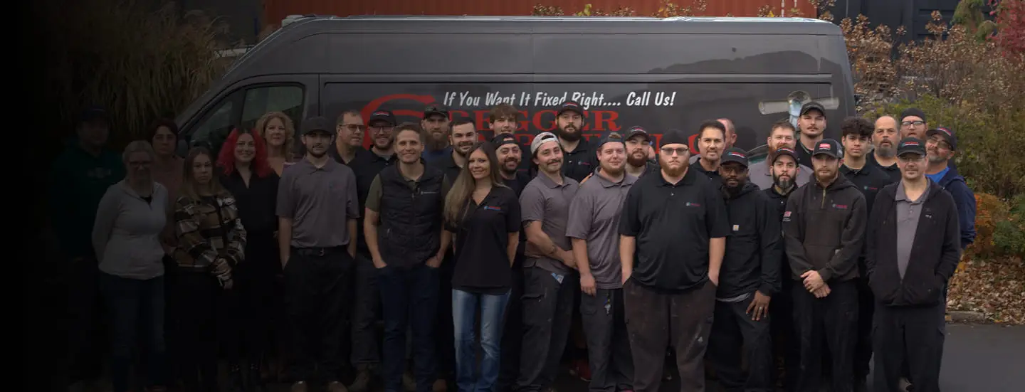 The Cregger team standing in front of a gray van with the Cregger logo and slogan. They wear casual work attire, smiling and looking at the camera. The setting is outdoors with autumn foliage.
